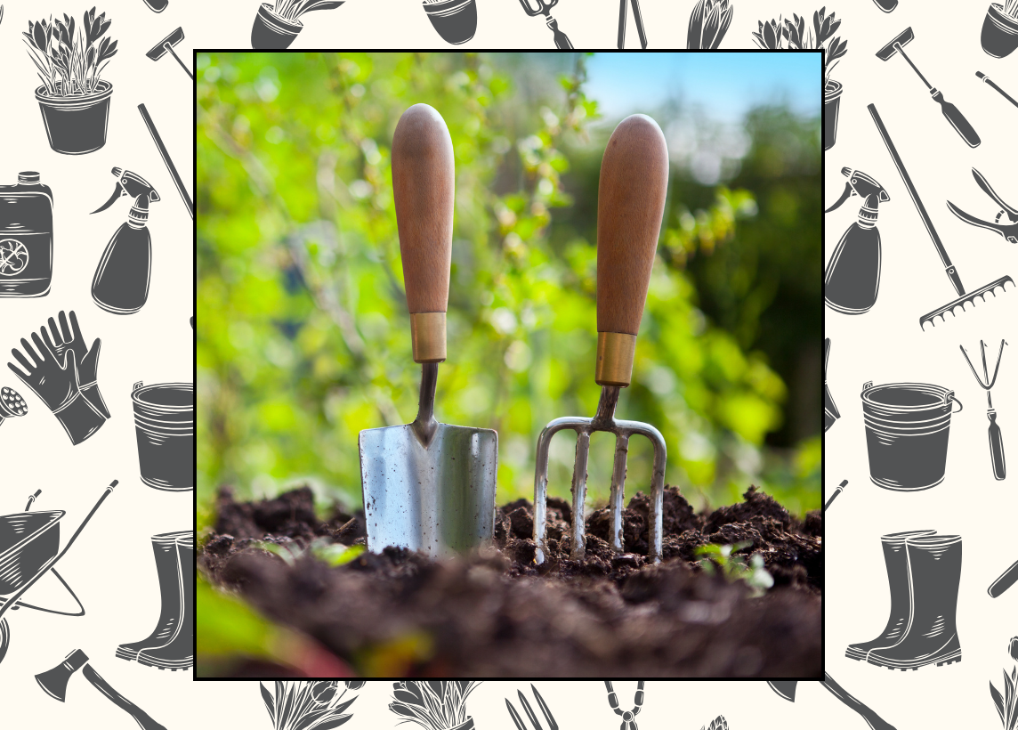 A trowel and small rake stand in a patch of freshly tilled dirt. Sun shines on greenery in the blurred background.