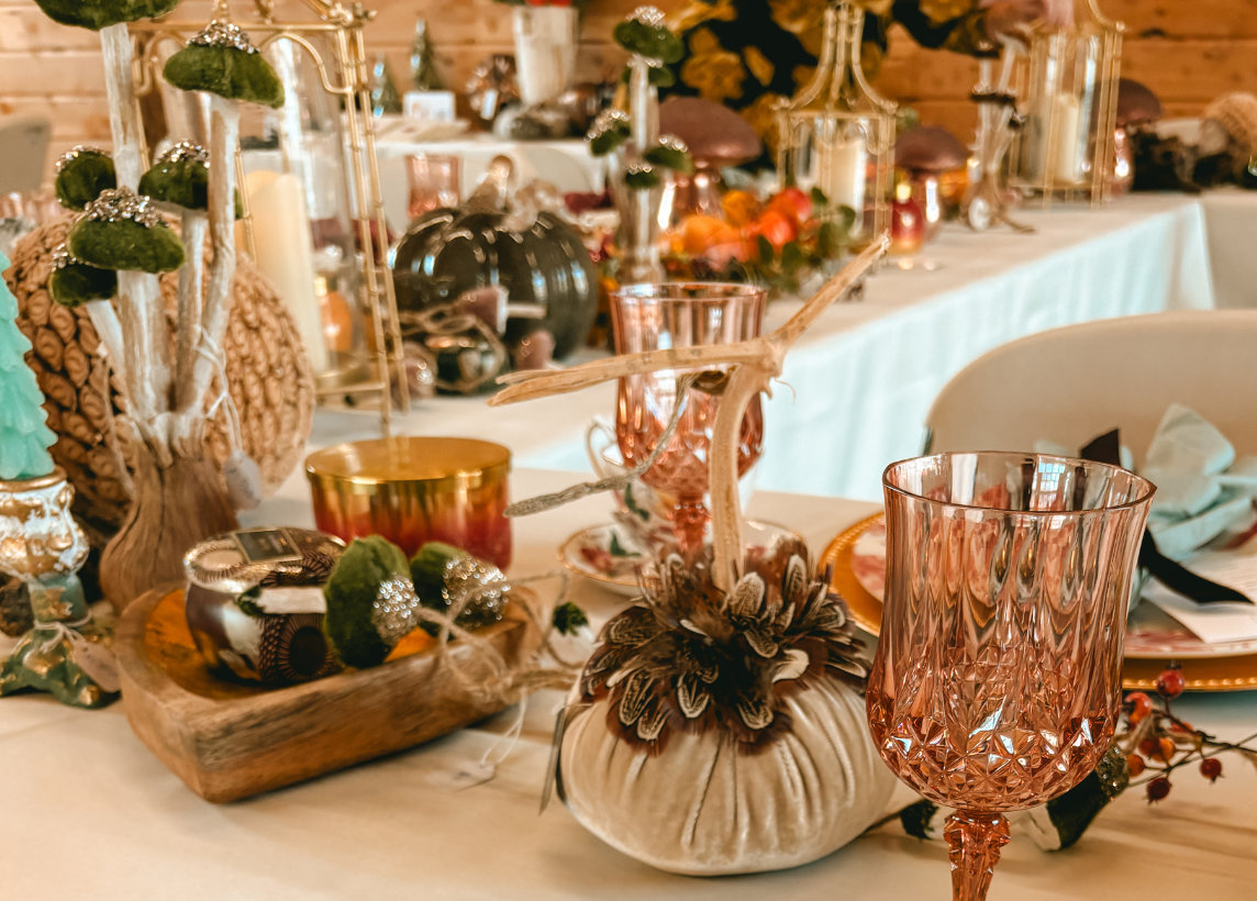A photo of a Fall table arrangement that includes decorative pumpkins and mushrooms, candles, and rose tinted glassware. This photo was taken at the 2024 Maestra Masterclass with Virtuosa Society featuring guest speaker Georgene Rice.