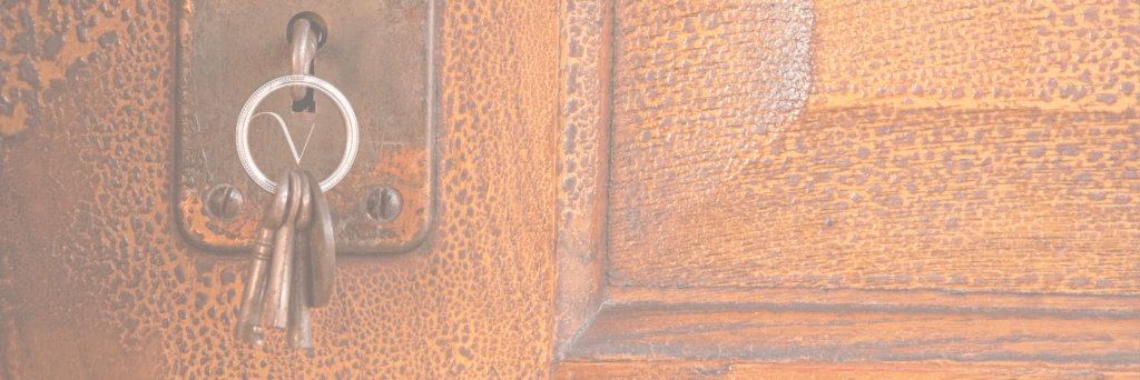 A faded image of a ring of skeleton keys, one of which is tucked into an old lock on a door with the rest hanging down. The Virtuosa Society logo, an encircled V, sits in the middle of the key ring.